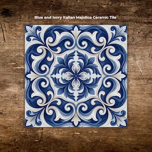 May include: Square blue and ivory Italian Majolica ceramic tile with a symmetrical floral design. The tile features a repeating pattern of swirling leaves and floral elements in shades of blue and ivory. The text "Blue and Ivory Italian Majolica Ceramic Tile" is at the top.