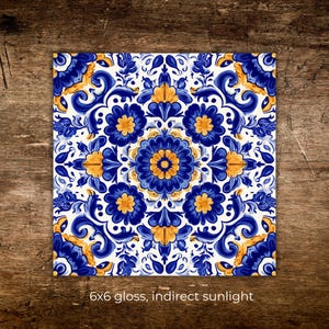 May include: Square ceramic tile with a symmetrical floral design in shades of blue and yellow against a white background. The tile measures 6x6 inches and has a glossy finish. The text "6x6 gloss, indirect sunlight" is at the bottom.