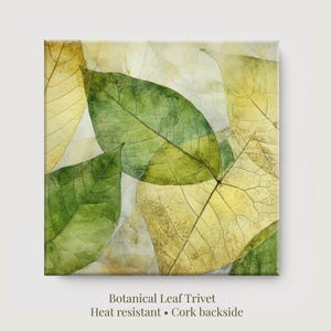 May include: Botanical leaf trivet featuring overlapping green and yellow leaves with a heat-resistant surface and cork backing. The trivet has a watercolor effect and is designed for kitchen use.