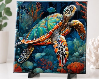May include: A square, colorful artwork featuring a sea turtle swimming underwater. The turtle has a vibrant shell with shades of blue, green, and orange. The background depicts coral, rocks, and other marine life in a deep blue sea.