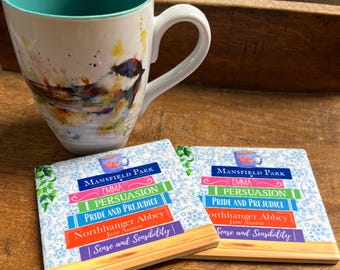 May include: A white ceramic mug with a teal interior and a bird painting, next to two square coasters. The coasters feature a floral design and the titles of Jane Austen novels: Mansfield Park, Emma, Persuasion, Pride and Prejudice, Northanger Abbey, and Sense and Sensibility.