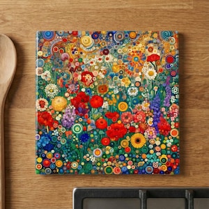 May include: Square decorative tile featuring a vibrant floral design. The artwork showcases a colorful array of flowers in shades of red, yellow, blue, and green, with a mosaic-like pattern. The tile is set against a wooden surface.