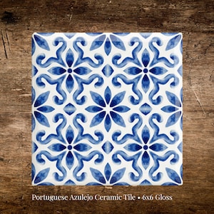 May include: A square, glossy ceramic tile with a white background and a repeating blue floral pattern. The tile measures 6x6 inches and features a Portuguese Azulejo design. The floral pattern is symmetrical and detailed.