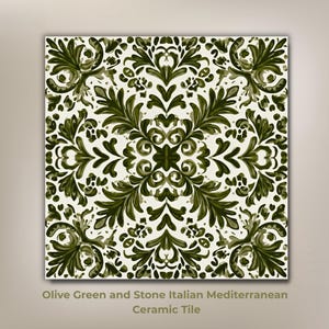 May include: Square ceramic tile with an olive green and stone Italian Mediterranean design. The tile features a symmetrical pattern of stylized leaves and floral elements against a white background. The text "Olive Green and Stone Italian Mediterranean Ceramic Tile" is at the bottom.