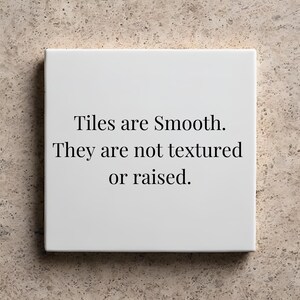 May include: A square, white tile with the text "Tiles are Smooth. They are not textured or raised." in black. The tile is set against a neutral, textured background.
