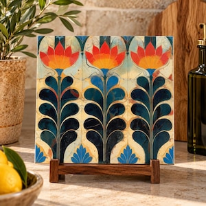 May include: A square ceramic tile featuring a repeating pattern of three stylized orange and yellow flowers with dark blue stems and leaves, set against a cream background. The tile is displayed upright on a small, dark brown wooden stand.