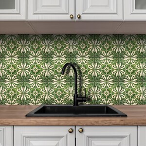 May include: A kitchen scene featuring a black sink and faucet set against a backdrop of green and white patterned tiles. White cabinets with gold knobs are visible below the countertop. The tiles have a floral design.