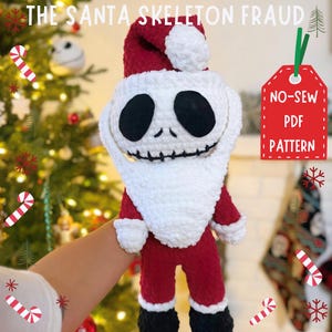 Könnte beinhalten: Gehäkelte Weihnachtsmannpuppe mit Skelettgesicht, trägt einen roten Anzug und einen weißen Bart. Die Puppe hält ein Schild mit der Aufschrift "No-Sew PDF Pattern".