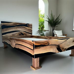 Könnte beinhalten: Ein handgefertigter Bettrahmen aus Holz mit einem Kopfteil. Das Bett hat ein natürliches Holzmaserungsmuster mit schwarzen Harzakzenten. Der Bettrahmen wird von vier Holzbeinen getragen. Das Gesamtdesign ist modern und rustikal.