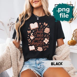Puede incluir: Camiseta negra con un diseño gráfico que presenta libros, lazos, una taza de café y el texto "Just one more chapter". El diseño es en tonos marrones y rosas. La camiseta es de estilo casual.