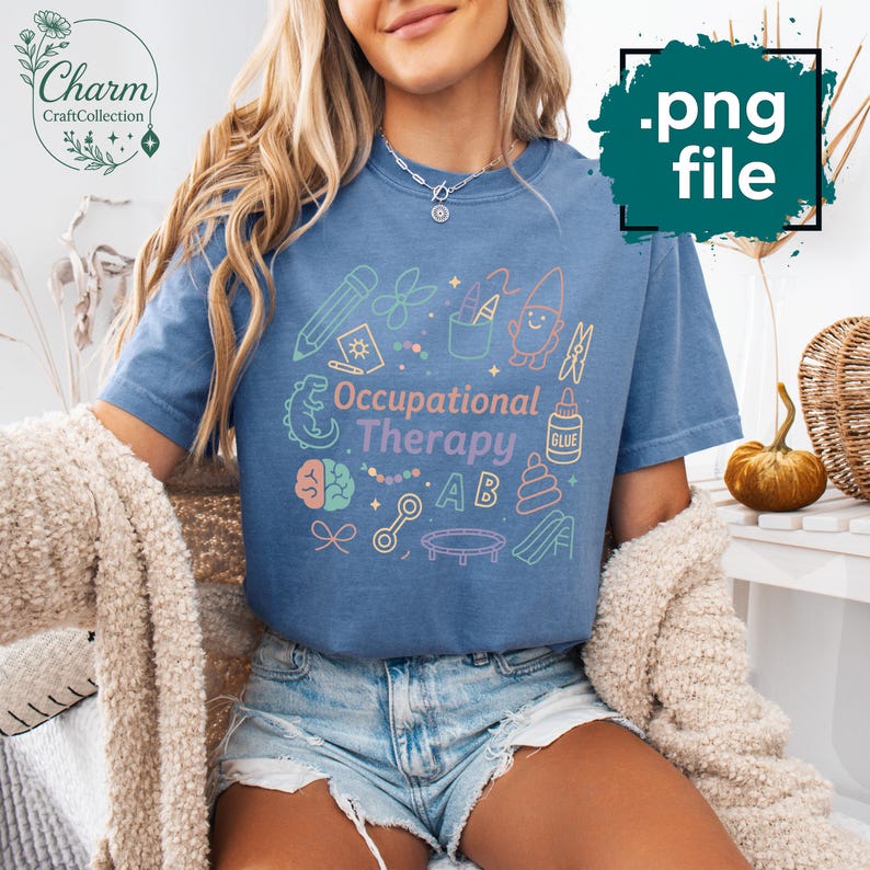 May include: A blue t-shirt with the words "Occupational Therapy" and related graphics in pastel colors. The design includes a pencil, scissors, a gnome, and other therapy-related images. The shirt is part of the Charm Craft Collection.