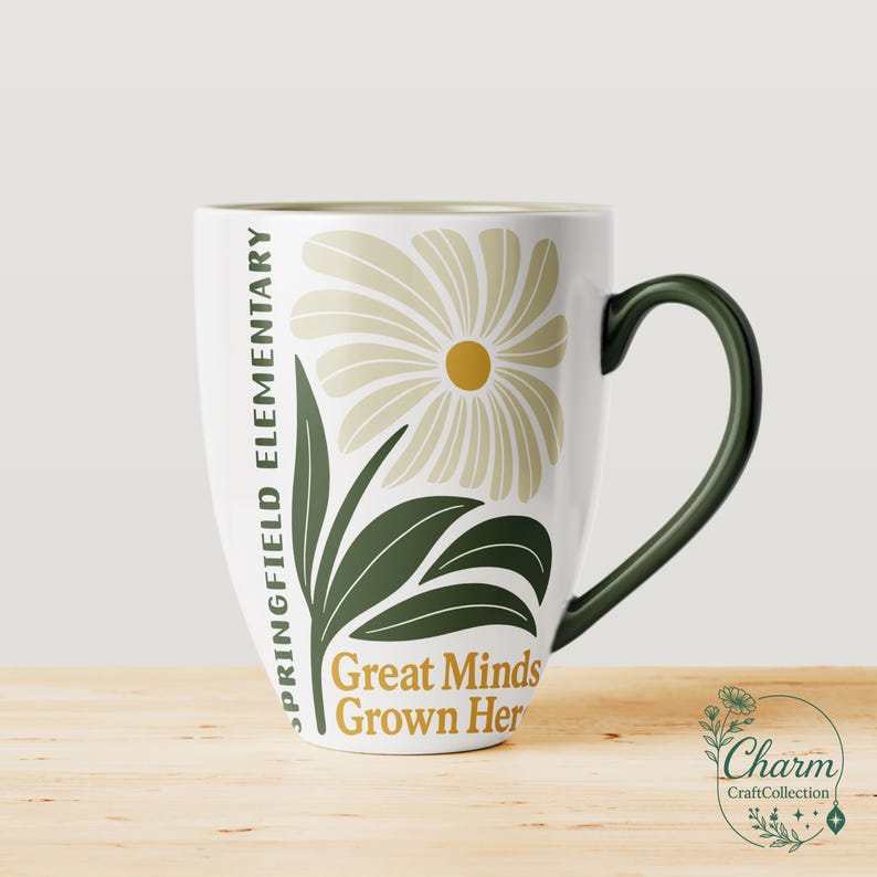 May include: White ceramic mug with a green handle and rim. The mug features a floral design with a daisy and leaves in shades of beige and green. Text on the mug reads "Springfield Elementary" and "Great Minds Grown Here."