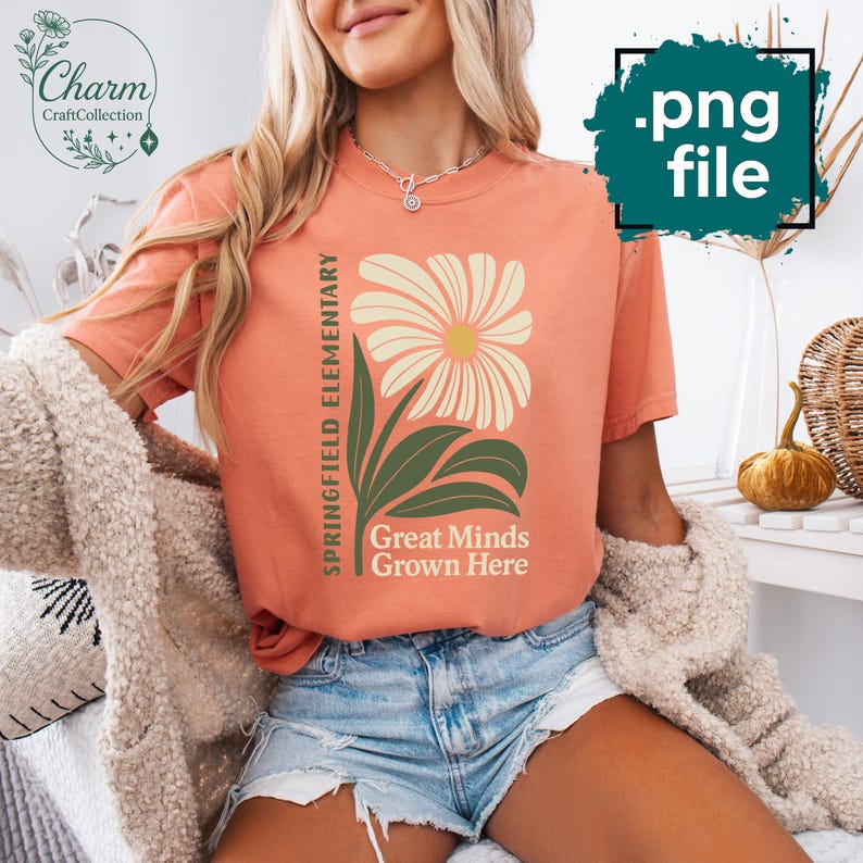 May include: A coral-colored t-shirt featuring a large floral design with the text "Springfield Elementary" and "Great Minds Grown Here." The flower has cream-colored petals and a yellow center, with green leaves and stem. The shirt is a .png file.