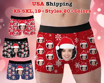 May include: Boxer briefs in red, black, and navy blue, each featuring a repeating pattern of a face wearing a Santa hat. The red briefs have a large face graphic and snowflake accents. The briefs have a black waistband.
