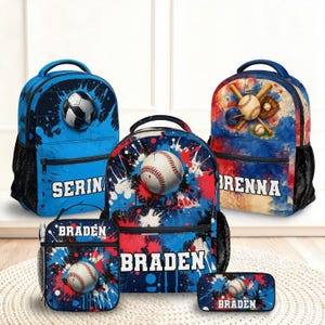 May include: Three backpacks, a lunch bag, and a pencil case featuring baseball-themed designs with blue, red, and white paint splatter patterns. The items are personalized with the names Serina, Brenna, and Braden in white block lettering.