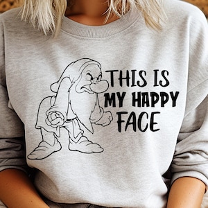 May include: A gray sweatshirt with a black and white illustration of a grumpy dwarf and the text "This is my happy face".