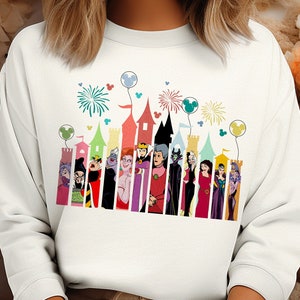 May include: White sweatshirt with a colorful graphic print of Disney villains in front of a castle silhouette. The graphic includes fireworks, balloons, and the text "Mickey Mouse" in a circle.