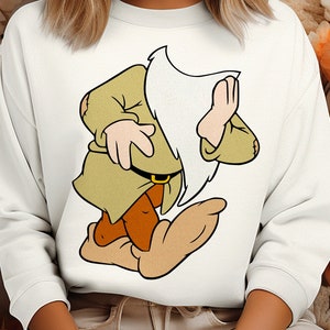 May include: White sweatshirt featuring a cartoon illustration of a dwarf character. The dwarf is depicted in a green tunic, brown pants, and large beige shoes. The design is centered on the front of the sweatshirt.