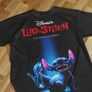 May include: Black t-shirt featuring the Disney's Lilo & Stitch logo in red and white. The shirt displays a blue Stitch character holding a glass slipper. The text "Si el zapato te queda..." is also printed on the shirt.