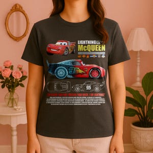 Puede incluir: Camiseta gris oscuro con un diseño de Rayo McQueen de la película Cars. El diseño incluye imágenes del coche de carreras y el texto "LIGHTNING MCQUEEN". La camiseta también tiene el texto "I'M FASTER THAN FAST, QUICKER THAN QUICK, I AM LIGHTNING!"