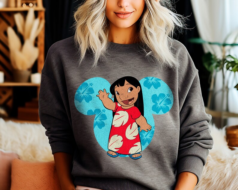 May include: A gray sweatshirt with a blue Mickey Mouse ear design featuring a cartoon character of Lilo from the Disney movie Lilo & Stitch. The character is wearing a red dress with white flowers and is waving.