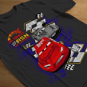 Puede incluir: Una camiseta negra con un diseño gráfico que presenta dos coches de carreras de dibujos animados. Los coches son rojos y grises con rayas de carreras negras. El texto "SPEED RSN RACE & SAFETY NETWORK" está impreso en amarillo, rojo y azul en la camiseta.