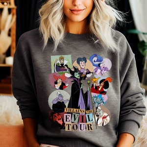 Puede incluir: Sudadera gris oscuro con un gr&aacute;fico colorido de villanos de Disney en marcos circulares. El gr&aacute;fico incluye personajes como Mal&eacute;fica y &Uacute;rsula, con el texto "Villains The Evil Tour" debajo. La sudadera est&aacute; hecha de un material suave.