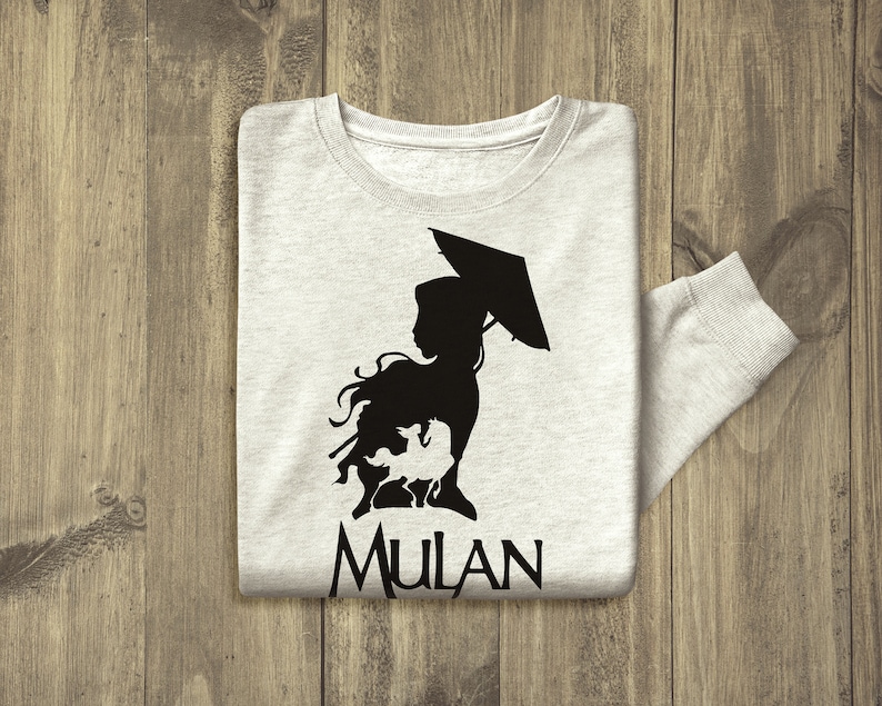 Op de afbeelding: Een grijs longsleeve t-shirt met een zwart silhouet van een vrouw die een paraplu en een draak vasthoudt. De tekst "MULAN" is onder het silhouet gedrukt.