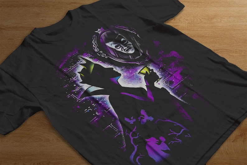 Puede incluir: Camiseta negra con una silueta de un personaje sosteniendo una copa, con un espejo y una cara en el fondo. El dise&ntilde;o incorpora acentos morados y blancos, con un tema c&oacute;smico y un toque de fantas&iacute;a.