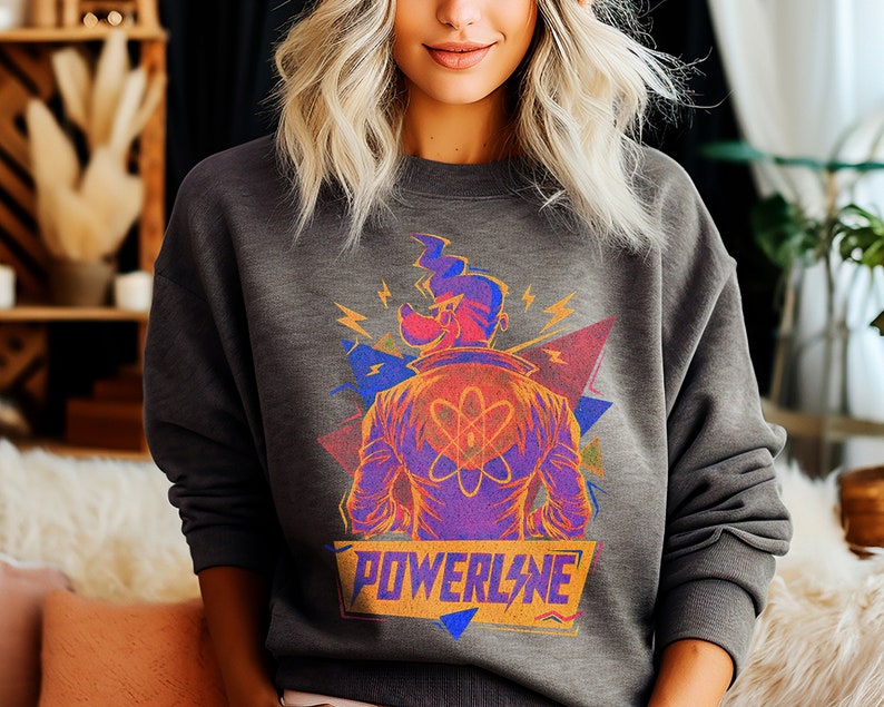 May include: A gray sweatshirt with a colorful graphic print of a cartoon character with a lightning bolt and the word "POWERLINE" in yellow letters.