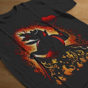 Puede incluir: Camiseta negra con la silueta de un personaje sosteniendo un cetro rojo en forma de coraz&oacute;n. El dise&ntilde;o incluye detalles en naranja y amarillo, representando una escena fant&aacute;stica.