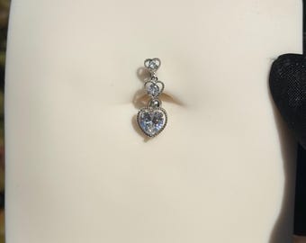 May include: A silver belly button ring with a cascade of heart-shaped gemstones. The largest heart is at the base, with smaller hearts above. The clear gemstones sparkle, set in a delicate metal frame.