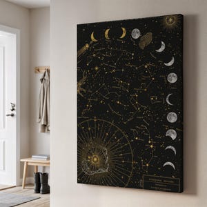 May include: A black canvas print featuring a celestial design with gold constellations, moon phases, and a sunburst. The artwork includes the text "STREYTINA MOSOON" and "COMPILATION". The print is displayed on a wall in a room.