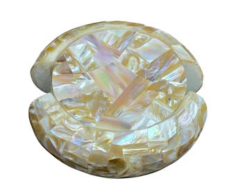 Può includere: Un set di sottobicchieri decorativi realizzati con tessere a mosaico iridescenti di madreperla. I sottobicchieri sono disposti a forma di conchiglia, con una lucentezza perlacea e un motivo a mosaico. Il set è progettato per proteggere le superfici dagli anelli delle bevande.