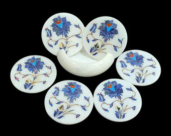 Può includere: Set di sei sottobicchieri rotondi in marmo bianco con intarsi floreali blu. I sottobicchieri presentano un motivo floreale centrale con dettagli dei petali. Include un portabicchieri in marmo bianco abbinato.