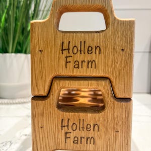 May include: A wooden egg crate with a handle, stacked on top of another identical crate. Both crates are labeled "Hollen Farm" in a dark brown font.