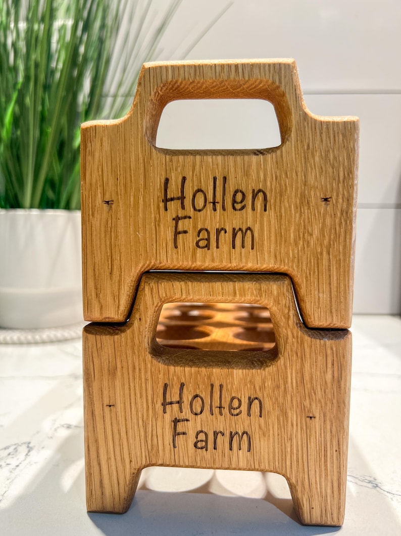 May include: A wooden egg crate with a handle, stacked on top of another identical crate. Both crates are labeled "Hollen Farm" in a dark brown font.