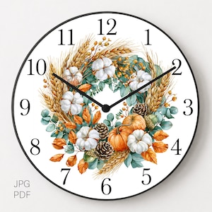 Pode incluir: Um relógio de parede redondo com moldura preta e mostrador branco com números pretos de 1 a 12. O centro apresenta uma ilustração em aguarela de uma coroa de colheita com flores de algodão brancas, abóboras cor de laranja e folhas verdes.