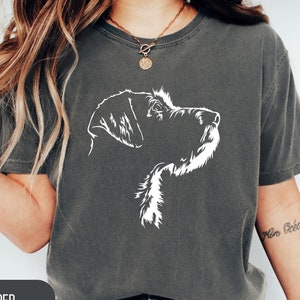 May include: A dark gray t-shirt with a white silhouette of a dog's head. The dog is looking to the right. The text "PEPPER" is visible in the lower left corner of the image.