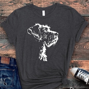 May include: A dark gray t-shirt with a white silhouette of a Wirehaired Pointing Griffon dog's head.