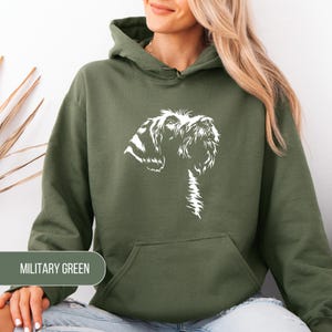May include: Military green hoodie with a white graphic of a dog's head and chest. The hoodie has a drawstring hood and a front pocket. The text "MILITARY GREEN" is displayed on the bottom left of the image.