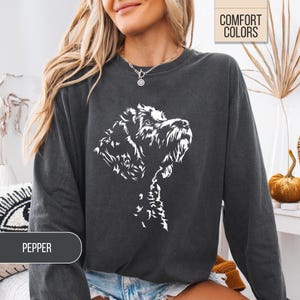 May include: Dark gray sweatshirt with a white graphic of a dog's head and chest. The word "PEPPER" is in a gray rectangle at the bottom left. The words "COMFORT COLORS" are in a tan rectangle at the top right.
