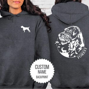 May include: A dark gray hooded sweatshirt with a white silhouette of a dog on the front and a white silhouette of a dog with the text "FOREST" on the back. The sweatshirt has a kangaroo pocket and a drawstring hood.