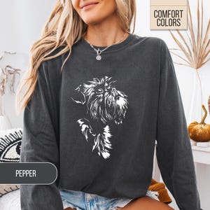 May include: Dark gray sweatshirt with a white graphic of a dog's face. The sweatshirt has long sleeves and a crew neck. The text "COMFORT COLORS" is in a box in the upper right corner. The word "PEPPER" is in a box at the bottom.