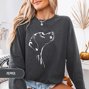May include: Dark gray sweatshirt featuring a white line drawing of a dog's head looking upwards. The word "PEPPER" is printed on a dark gray rectangle at the bottom left. The sweatshirt has long sleeves and a crew neck.