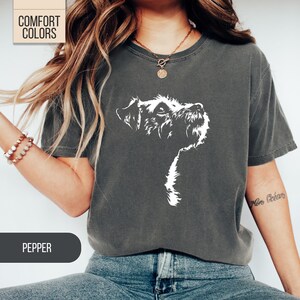 May include: Dark grey t-shirt with a white graphic of a dog's head and neck. The shirt has the text "COMFORT COLORS" in a white box at the top left and the word "PEPPER" in a black box at the bottom left.