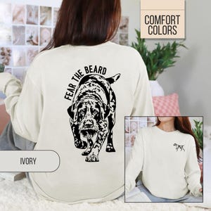 May include: Ivory-colored sweatshirt with a black and white dog graphic and the text "FEAR THE BEARD." The sweatshirt also features a small dog graphic on the front. The words "COMFORT COLORS" are in a box in the upper right corner.