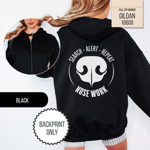 May include: A black full-zip hooded sweatshirt featuring a white graphic on the back of a dog nose with the text SEARCH - ALERT - REPEAT NOSE WORK. The front view shows a black hooded sweatshirt with a silver zipper and black drawstring cords.