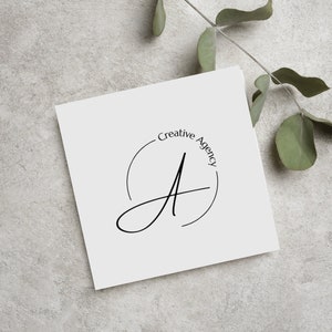 May include: A white card with a black and white logo that says "Creative Agency" in a circle around a stylized letter "A".
