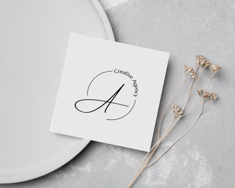 May include: A white card with a black circle containing a stylised letter A and the text "Creative Agency" in a circle around the letter.